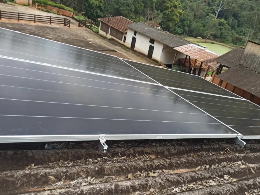 Usina solar instalada pela Sollivre em telhado de fibrocimento numa propriedade rural, com quatro módulos e a sede da fazenda ao fundo